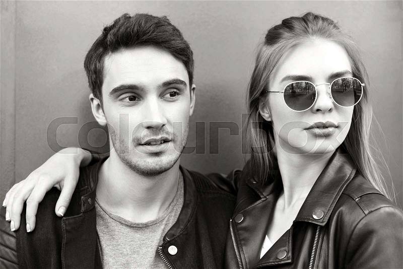 Black and white portrait of stylish young couple in love looking away, stock photo