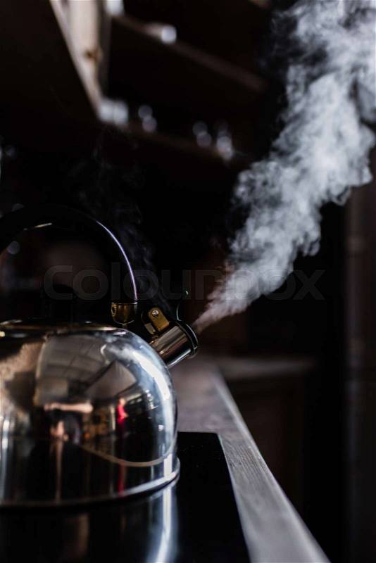 Close-up view of metallic kettle boiling on electric stove, stock photo