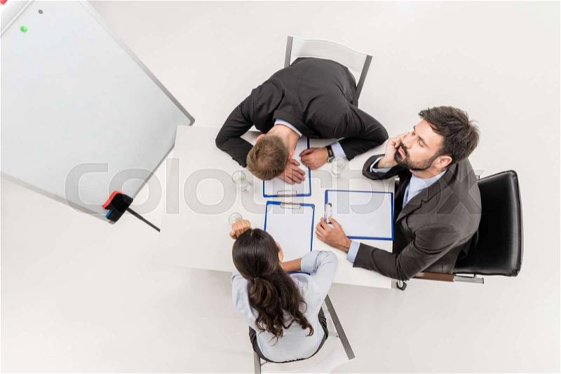 Overhead view of tired business people sitting at workplace during meeting isolated on white, stock photo
