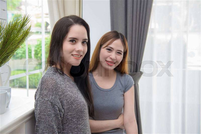 Portrait of two young woman standing in living room at home, stock photo