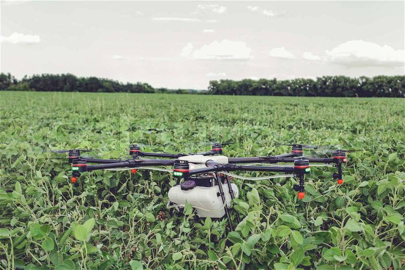Professional agriculture drone stands on the ground green field. Octocopter flight preparation, stock photo