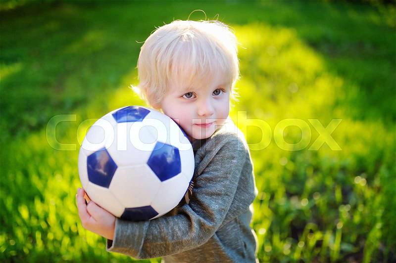 Little boy having fun playing a soccer game on sunny summer day. Active outdoors game for toddler and family with kids, stock photo