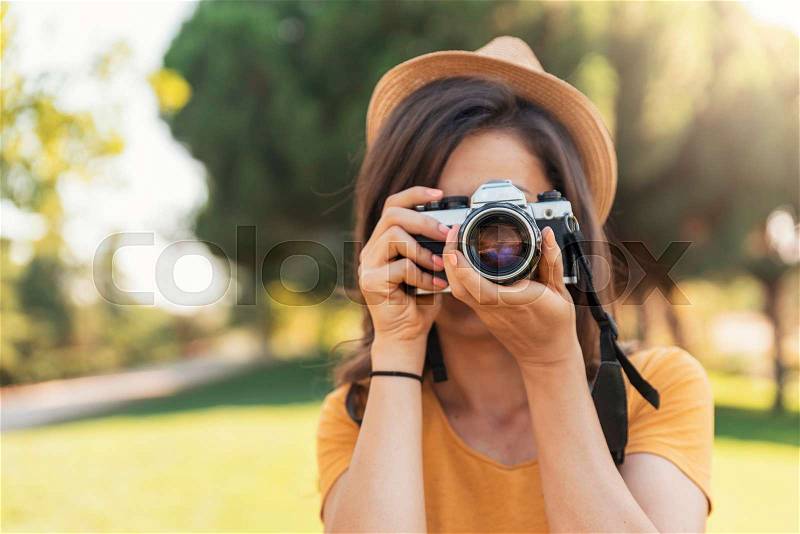 Young woman using a camera to take photo at the park, stock photo