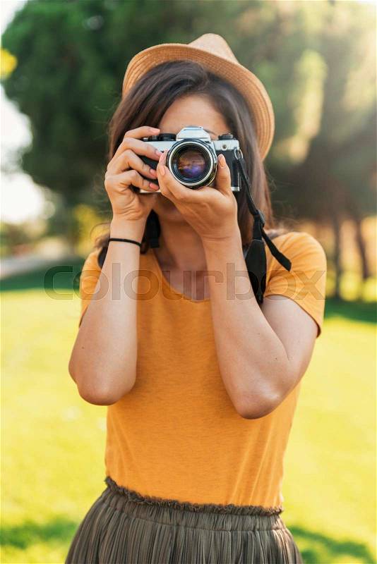 Young woman using a camera to take photo at the park, stock photo