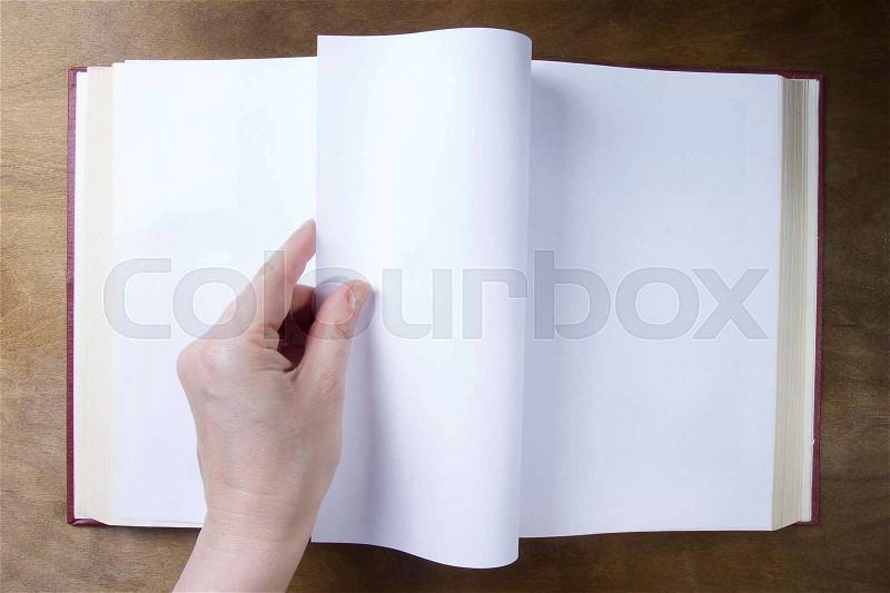 Hand turns the blank sheet of books on a wooden table, stock photo