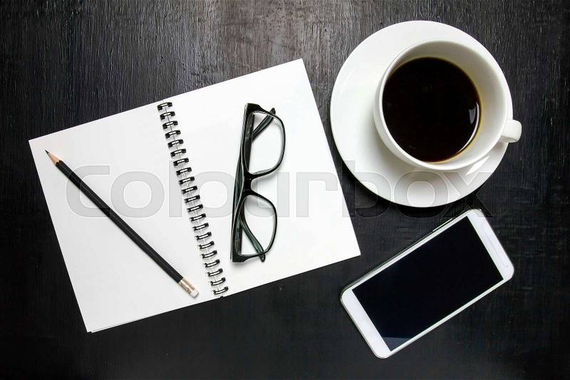 Top view of office desk workspace with coffee cup, notebook, pencil ,mobile phone ,glasses on wooden background, stock photo