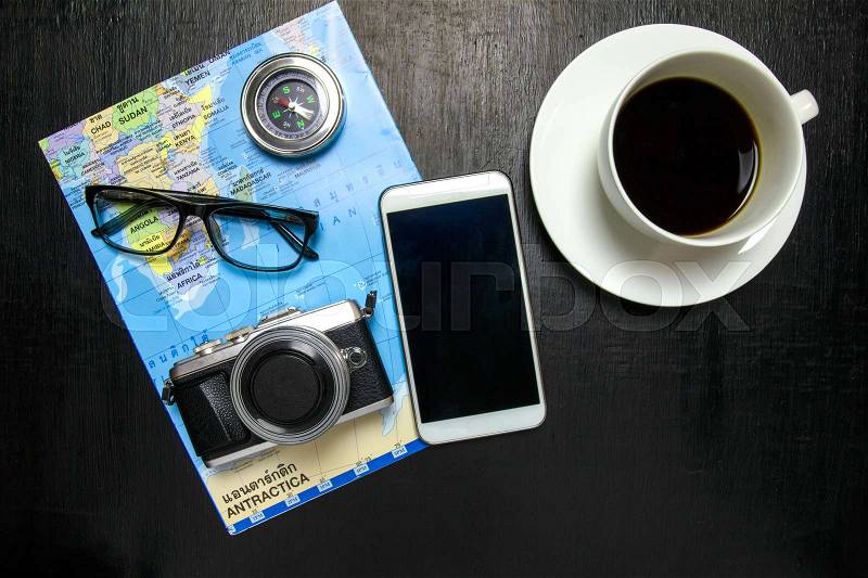 Top view of office desk workspace with coffee cup, camera ,world map ,compass,notebook,pencil ,glasses on wooden background, stock photo