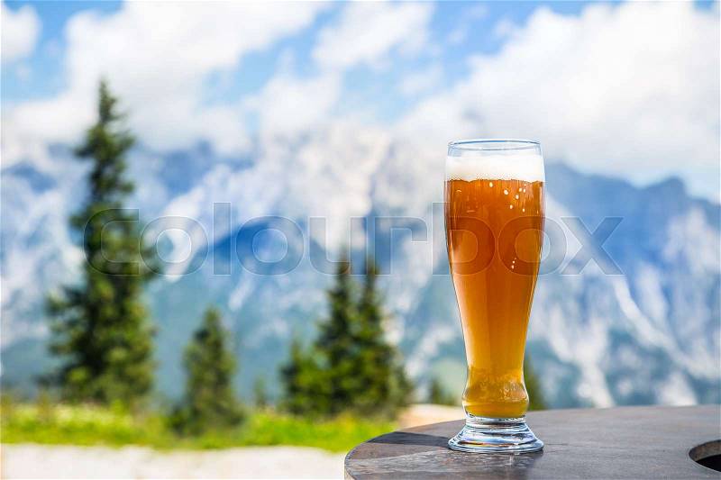 Beer. Cold golden draft beer in glass over alps. Tasty beer and tourist season in the mountains or the Alps, stock photo