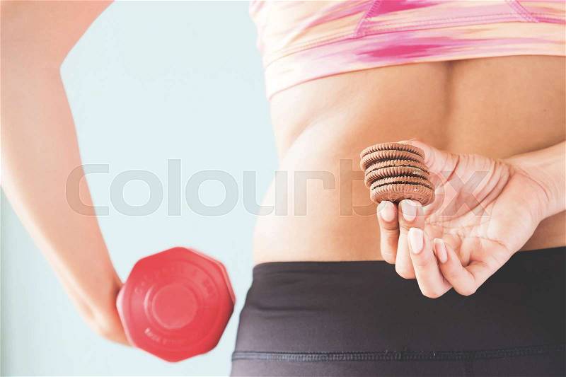 Healthy lifestyle concept, Diet and fitness, Fitness female holding snack and dumbbell in other hand, stock photo