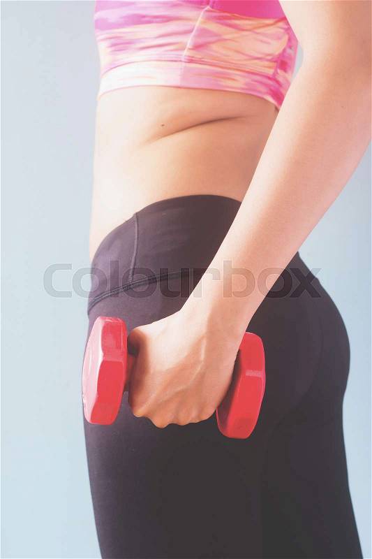 Fitness female in black pants and pink sport bra holding red dumbbell, stock photo