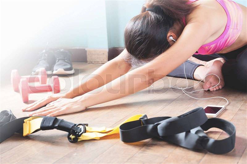 Fitness female in black pants and pink sport bra stretching after workout with copy space, stock photo