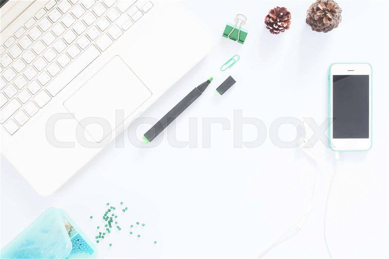 Office desk table with laptop, mobile phone, supplies, pine cone, green cap, glass beads. Top view with copy space, stock photo