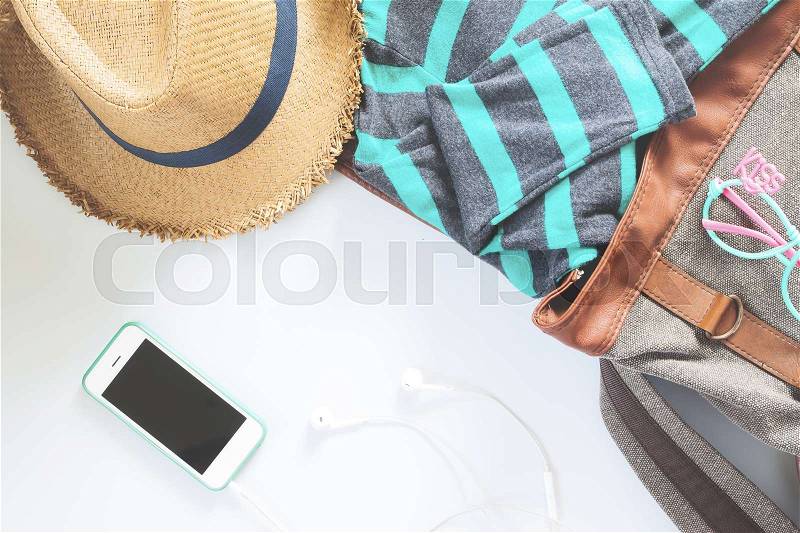 Flat lay female clothes and accessories collage with t-shirt, fashion glasses, hat, with mobile phone and earphone on white background, stock photo