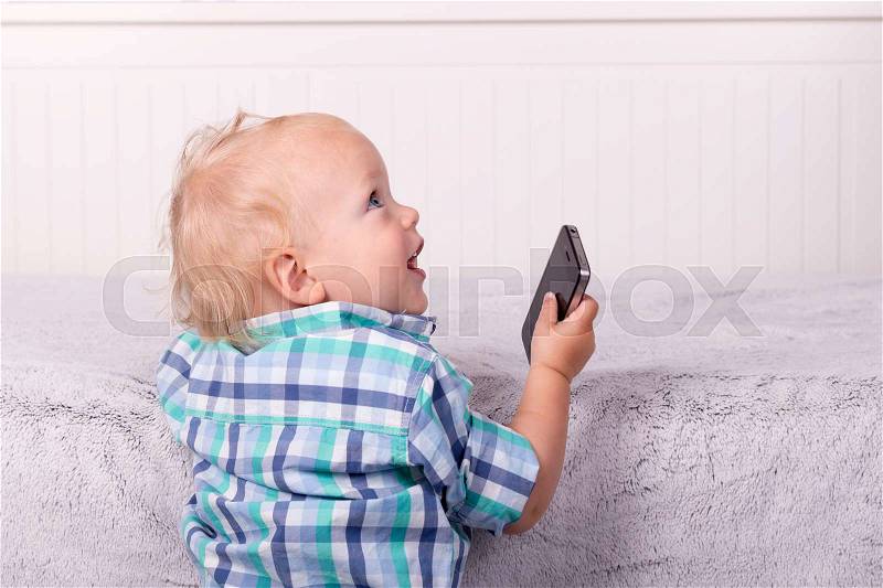 Funny toddler playing with a phone. Home shot, stock photo