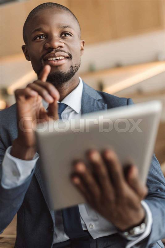 Handsome african american businessman having idea while working with digital tablet , stock photo