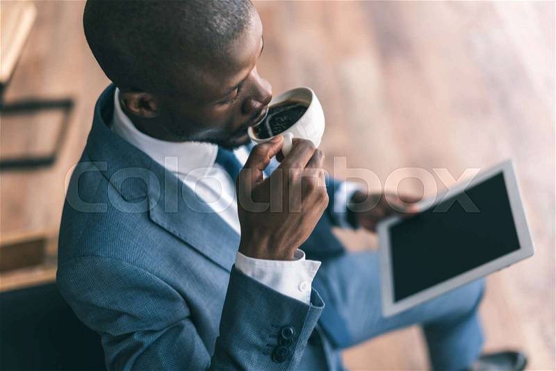 Handsome african american businessman using digital tablet and drinking coffee in cafe , stock photo