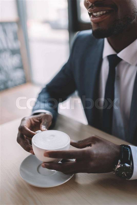 Cropped view of african american businessman holding coffee cup in cafe, stock photo