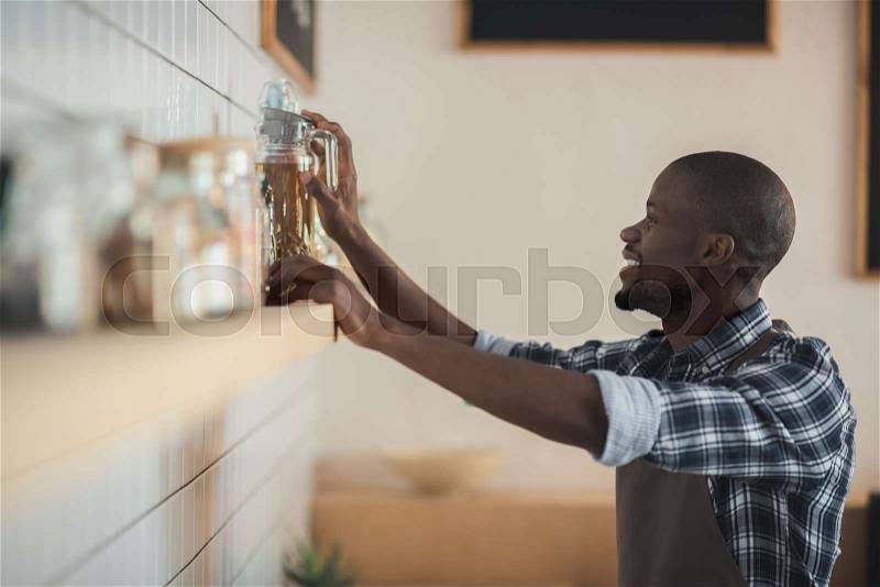 Handsome smiling african american barista working in cafe , stock photo