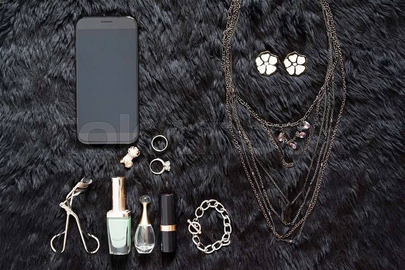 Mobile device in black color with beauty essential on black, Beauty items and cosmetics, stock photo