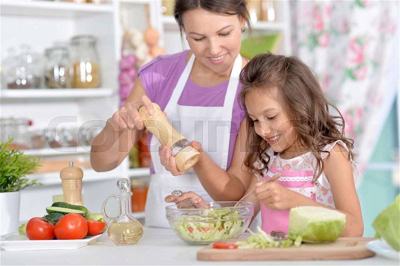 Mother and daughter preparing dinner together on kitchen, stock photo