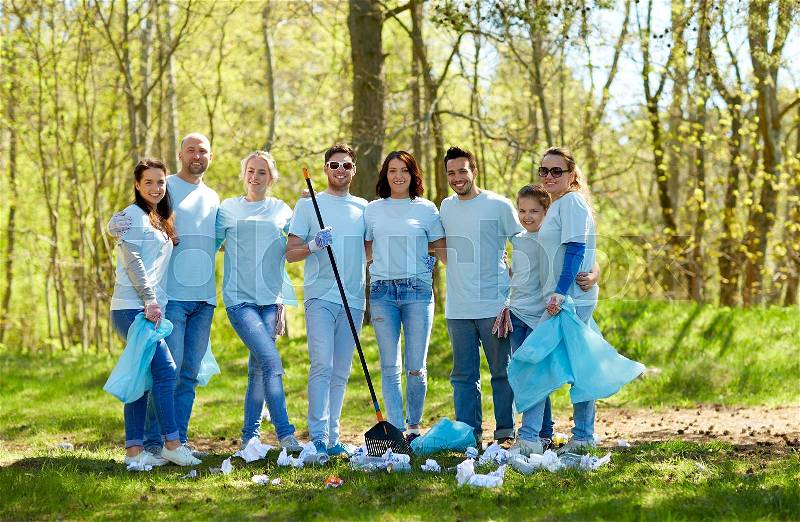 Volunteering, charity, cleaning, people and ecology concept - group of happy volunteers with garbage bags and rake in park, stock photo