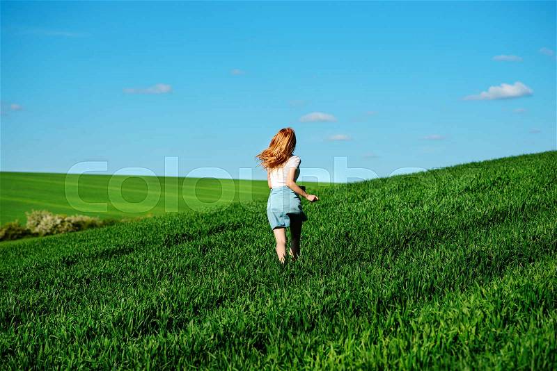 Young beautiful woman running on a green field, stock photo