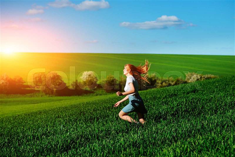 Young beautiful woman running on a green field, stock photo