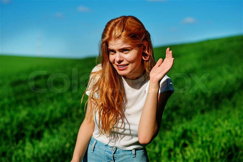 Beautiful woman in the nature tries to understand somebody by trying to hear something with putting her hand to her ears, stock photo