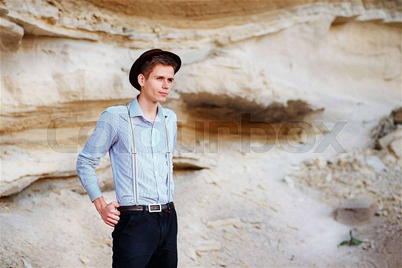 Stylish attractive man stands in the middle of a sand quarry and poses on the camera, stock photo