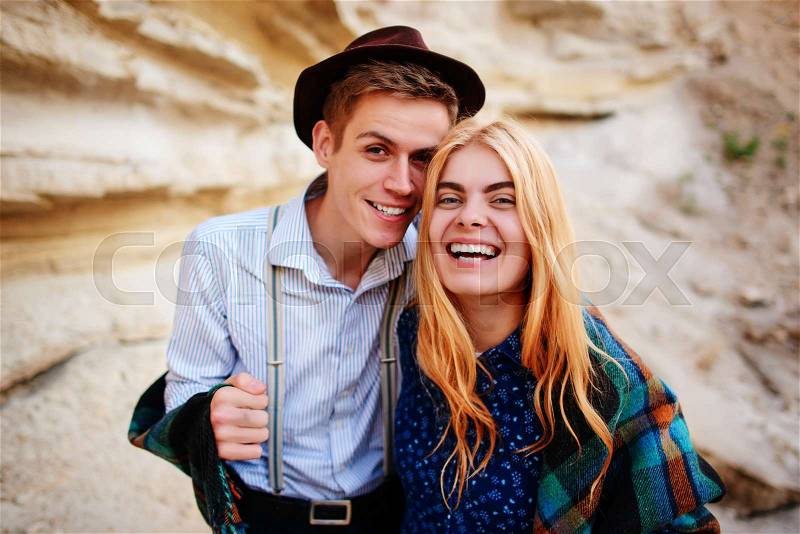 Handsome man and beautiful woman smiling into the camera in the middle of a sandy canyon, stock photo