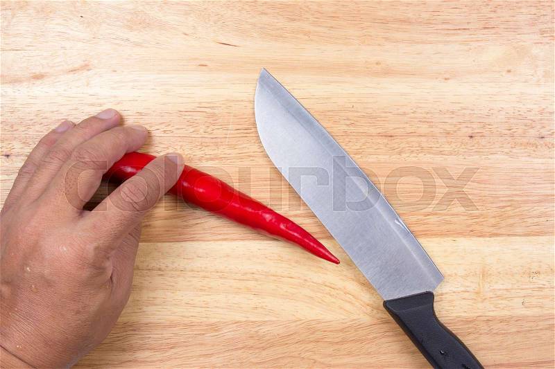 Hand cutting Hot Chili Peppers on wooden broad / Cooking green curry concept, stock photo
