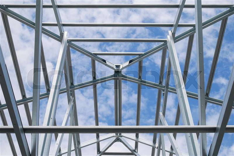 Structure of steel roof frame with blue sky and clouds at construction site, stock photo