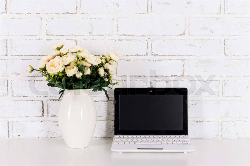 Workplace with modern laptop with blank screen over white brick wall background, stock photo