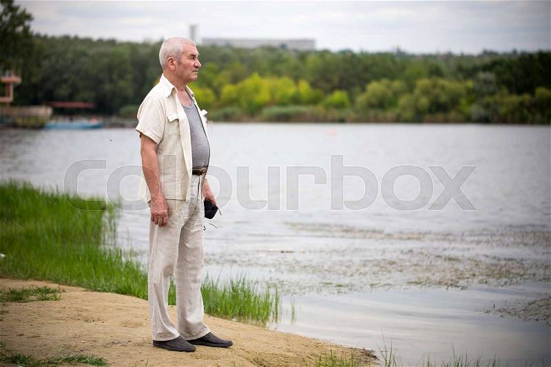Old man staying near park lake. Photo can be used as a whole background, stock photo