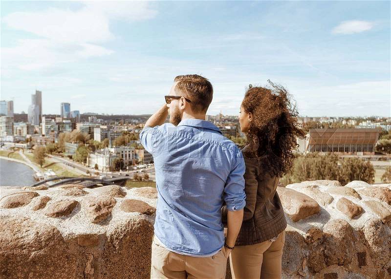 Young multiracial couple looking at city skyline as diversity friendship and togetherness travel concept , stock photo