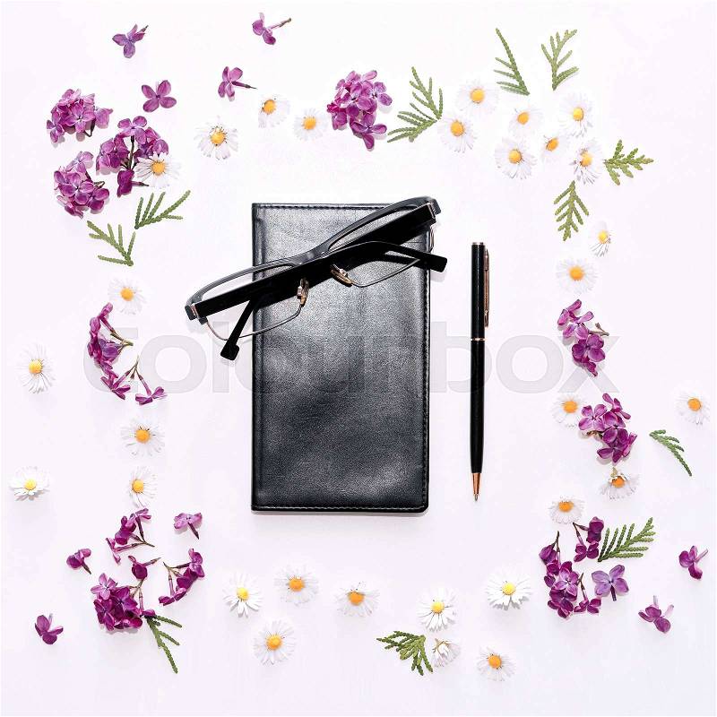 Pattern with diary, glasses, pen and lilac flowers on the white table background. Flat lay, top view, stock photo