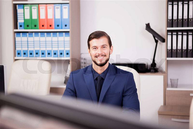 Happy entrepreneur in business suit at his work place. Image of succesful positive businessman at his new modern office, stock photo