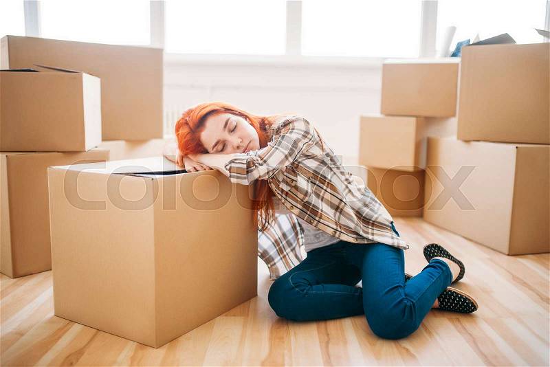 Tired woman sleeps on carton box, housewarming. Moving to new house, stock photo