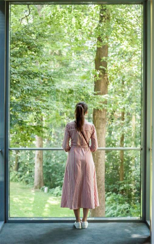 Woman looking into the window on sunny green forest, stock photo