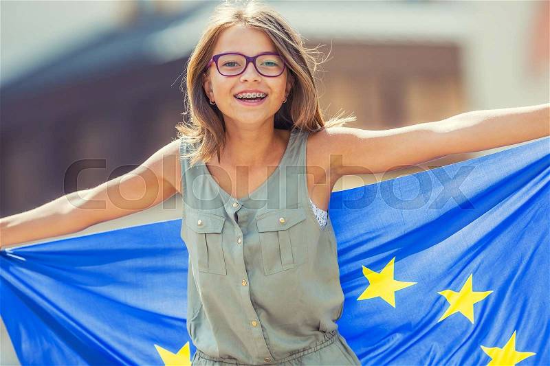 EU Flag. Cute happy girl with the flag of the European Union. Young teenage girl waving with the European Union flag in the city, stock photo