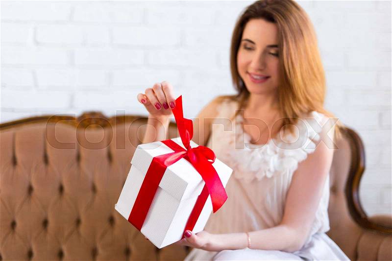 Holiday concept - beautiful woman opening gift box at home, stock photo
