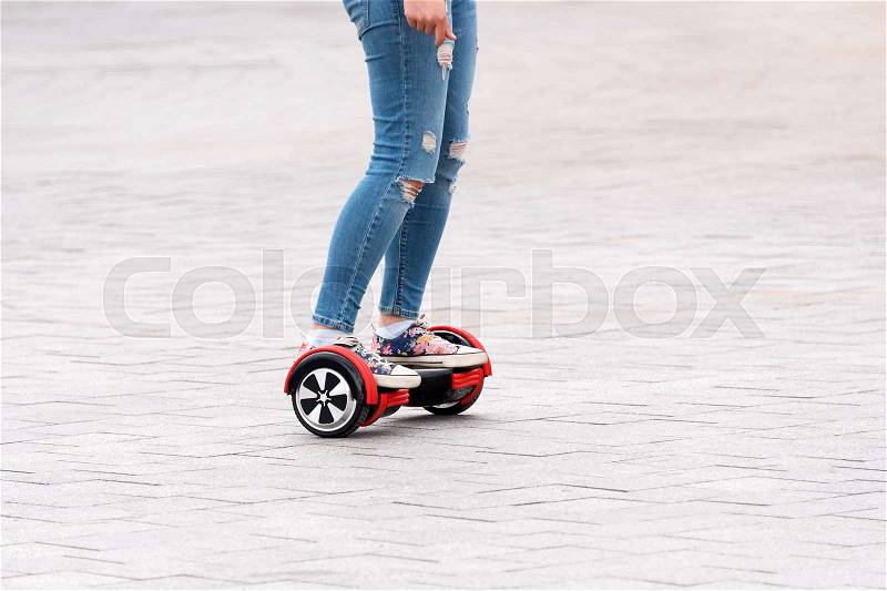 Young woman riding a hoverboard on the city square. New movement and transport technologies. Close up of dual wheel self balancing electric skateboard. People on electrical scooter outdoors, stock photo