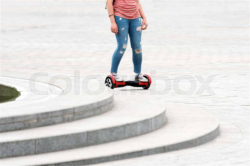 Young woman riding a hoverboard on the city square. New movement and transport technologies. Close up of dual wheel self balancing electric skateboard. People on electrical scooter outdoors, stock photo