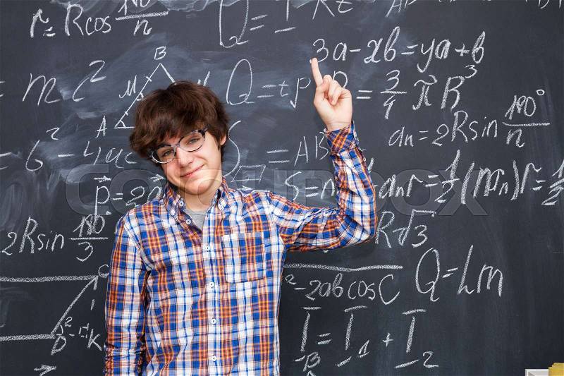 Hnadsome boy in glasses, blackboard filled with math formulas background, stock photo