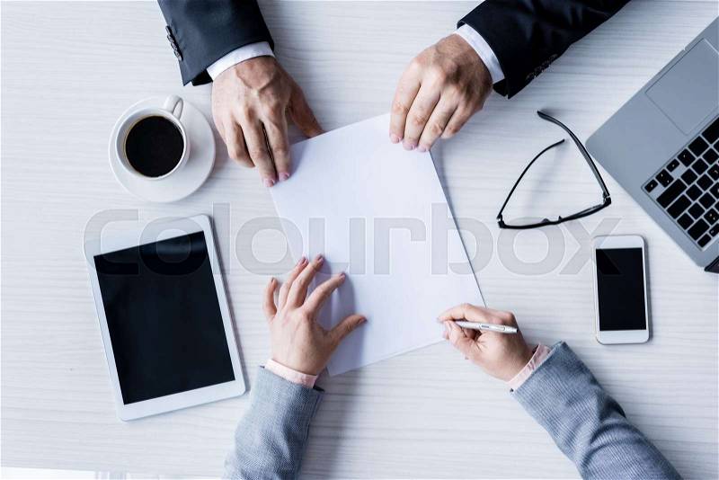 Top view of business partners signing contract during meeting, stock photo