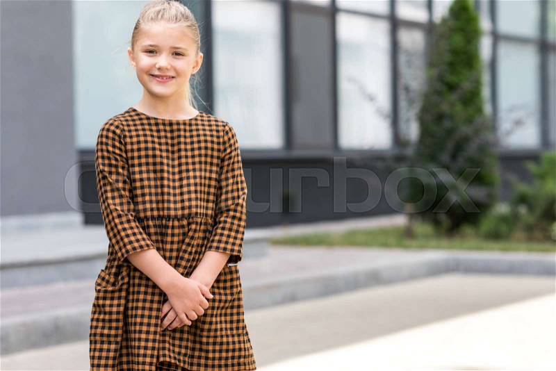 Portrait of beautiful blonde girl in dress standing outside and looking at camera, stock photo