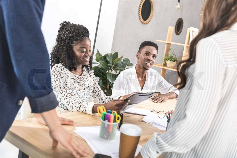 Smiling african american colleagues at business meeting at workplace in office, stock photo