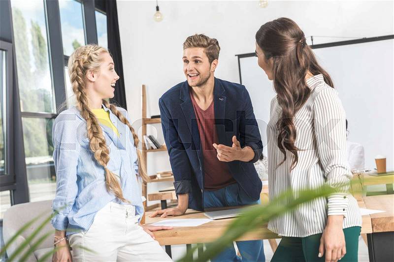 Multicultural young business people having conversation at workplace in office, stock photo
