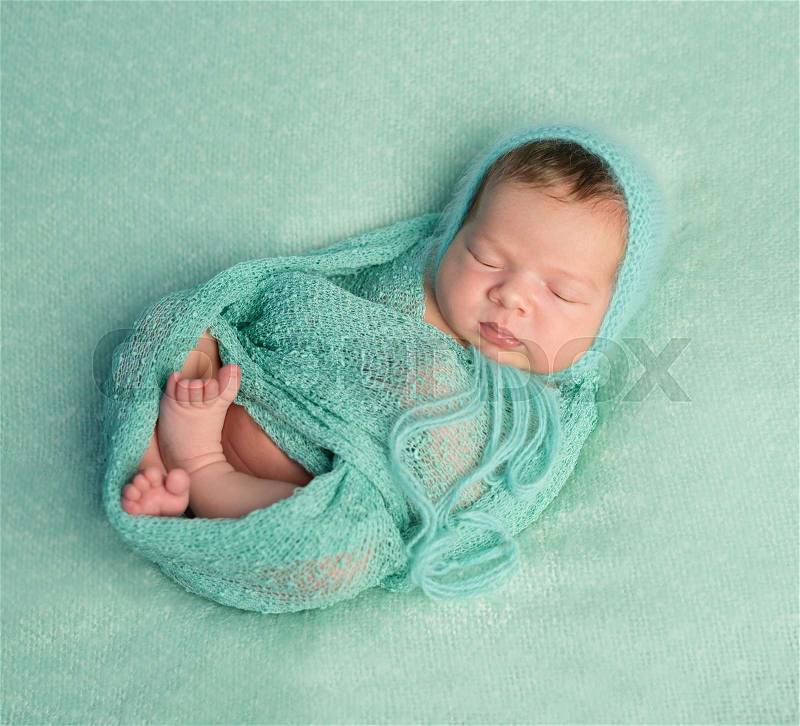 Funny sleeping newborn baby on blue blanket and wrapped in wooled diaper, stock photo