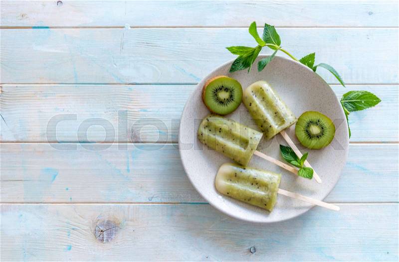Plate of homemade ice cream with kiwi, some mint leaves, copyspace left, topview, stock photo
